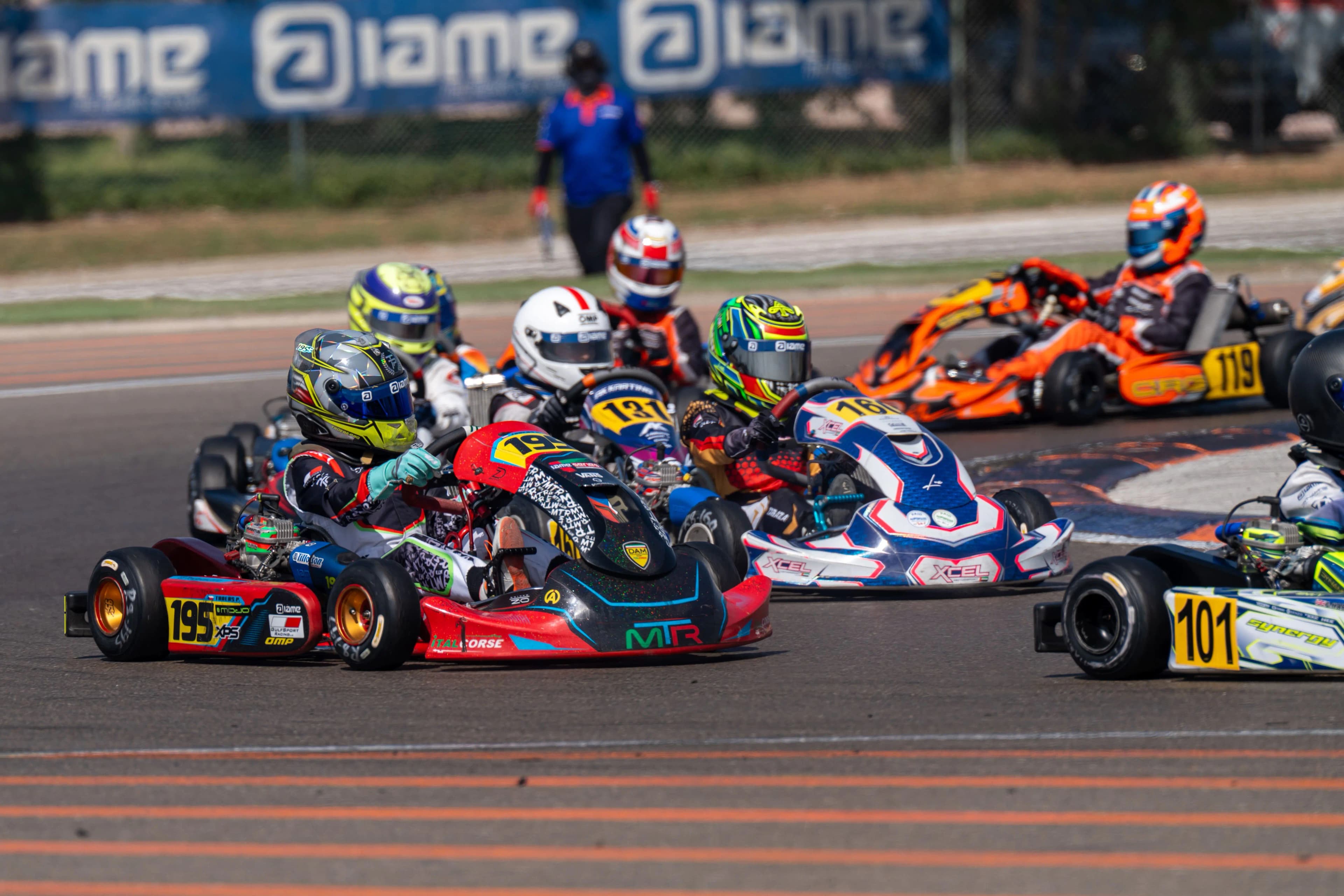 Karts racing wheel-to-wheel through a corner at a UAE round