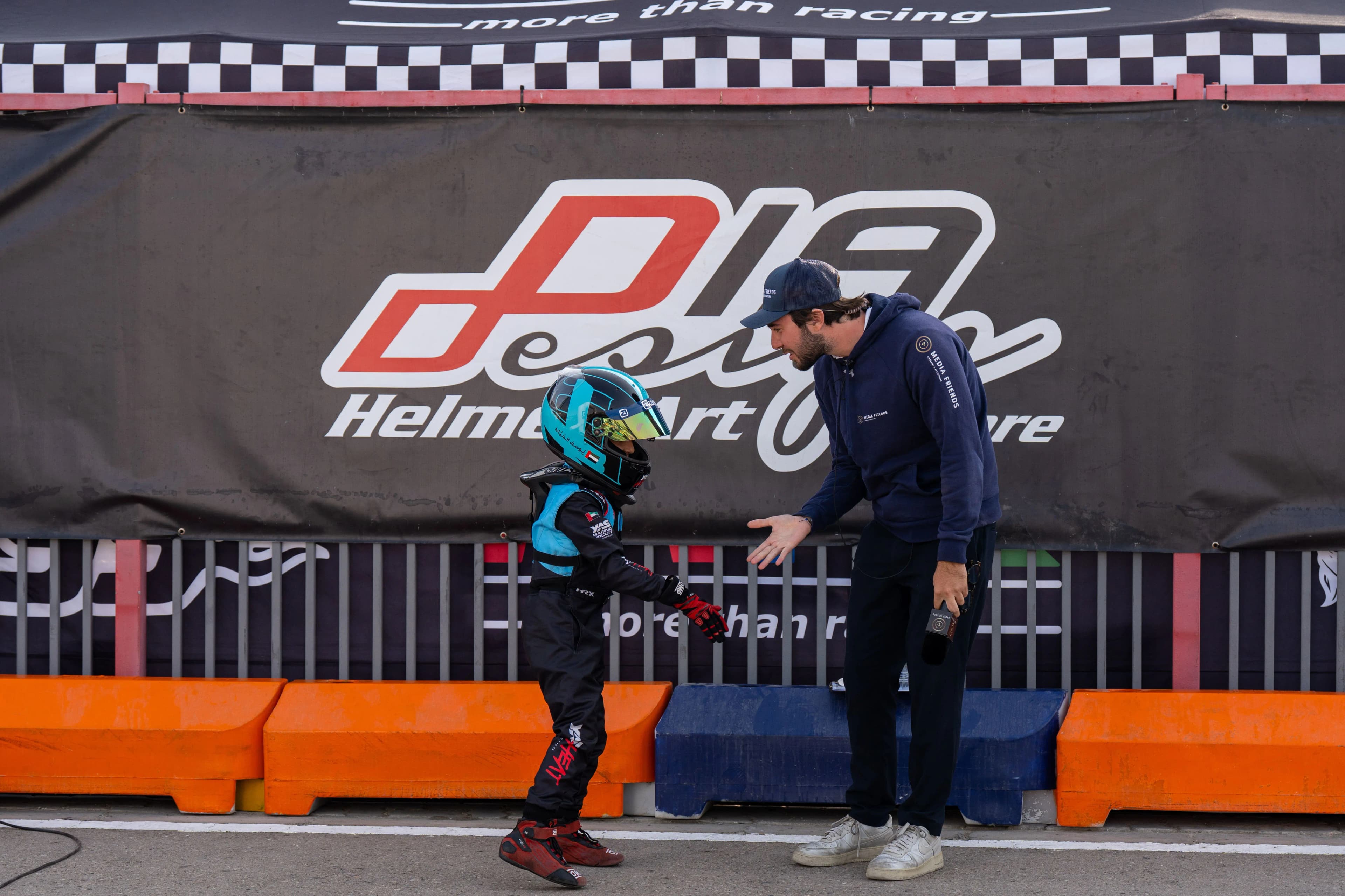 A young driver in helmet and race suit greeted trackside after a race