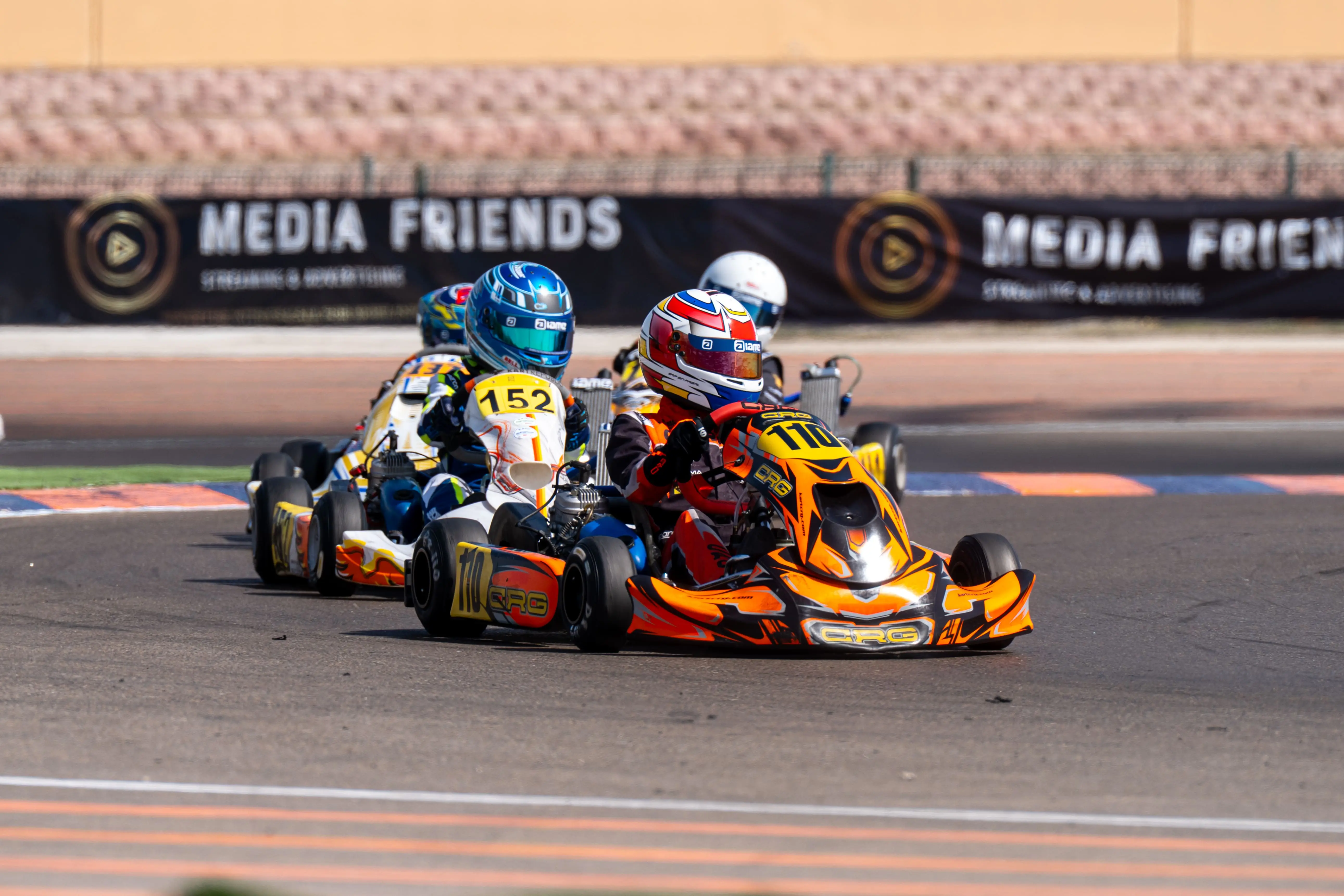 Two karts nose to tail past the Media Friends boards